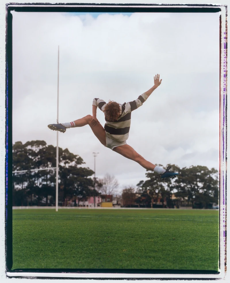 A performer leaps across the sky between football goalposts.